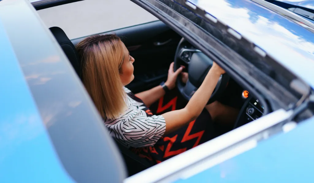 View of a driving woman through sunroof