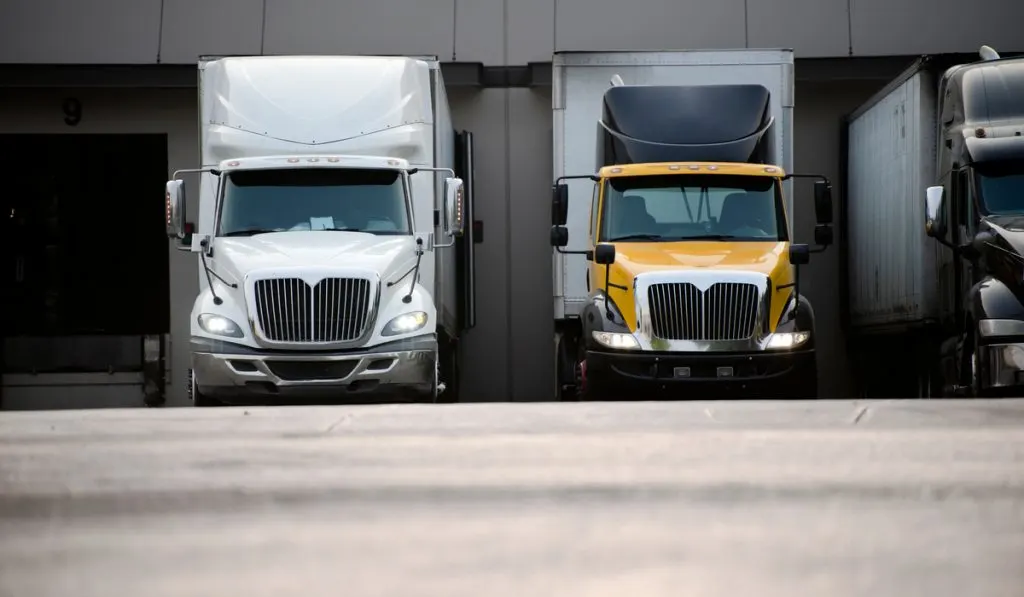 Different color semi-truck on parking space