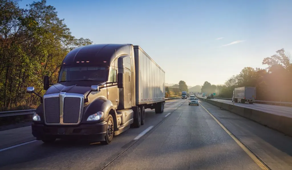 black semi-truck on road sunset 