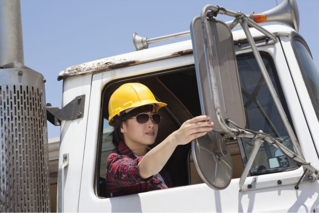 female industrial worker adjusting side mirror truck 