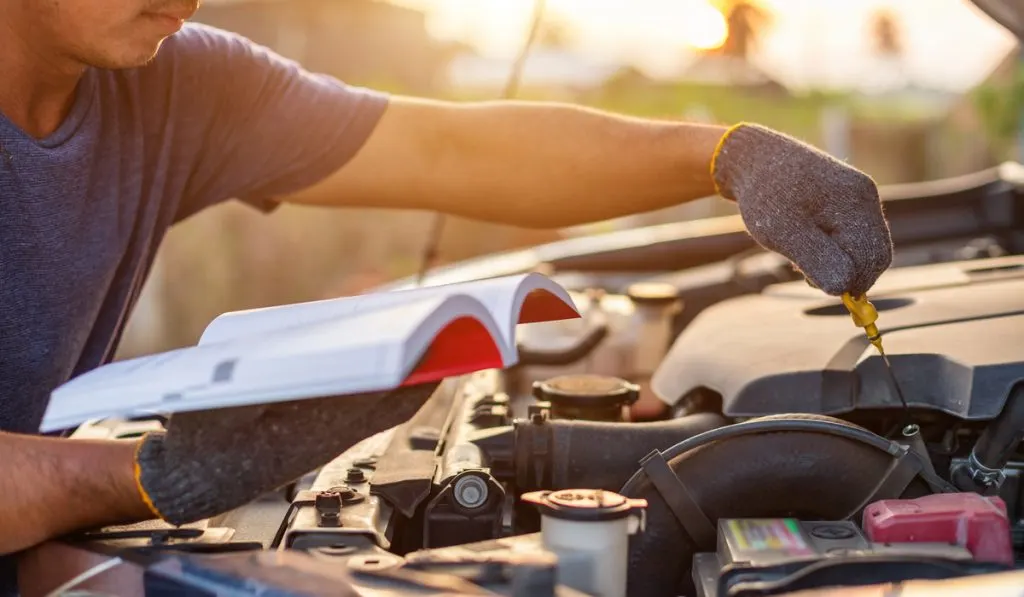 man holding reading car user manual 