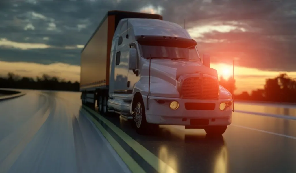 white yellow semi-truck on road sunset 