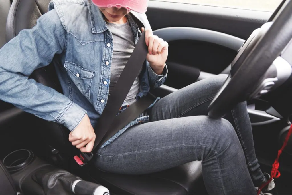 young lady wearing jeans clothes fastens seat belt