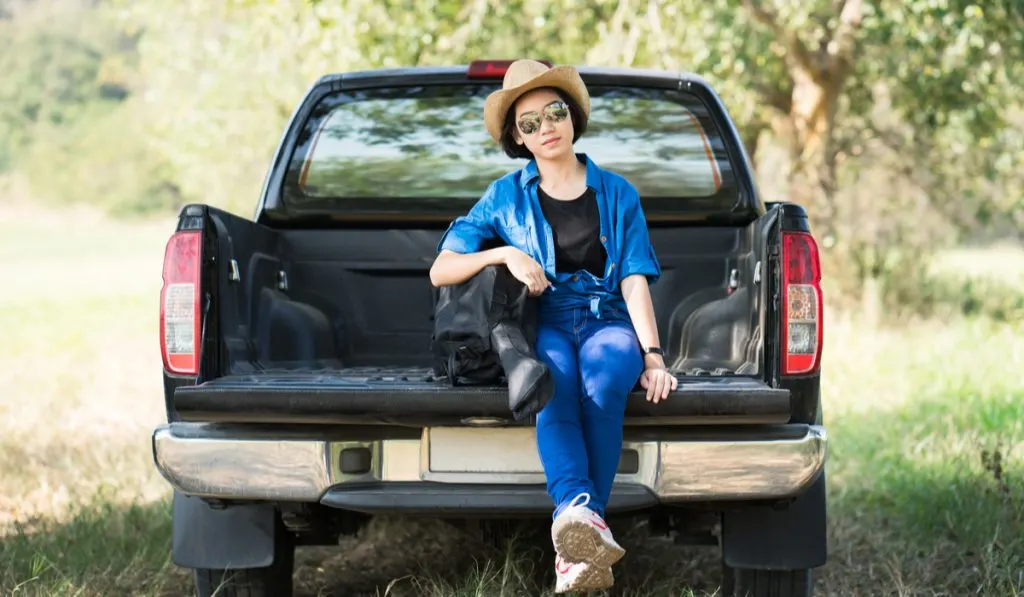 young woman short hair with hat sitting back of pickup truck
