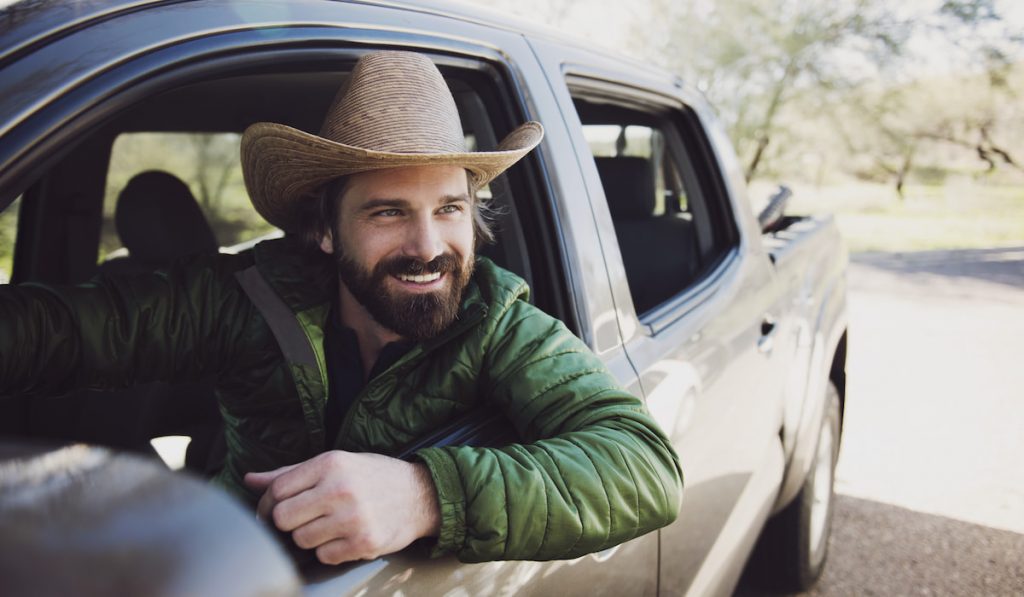 Happy Man Sitting In Pick-up Truck On Road
