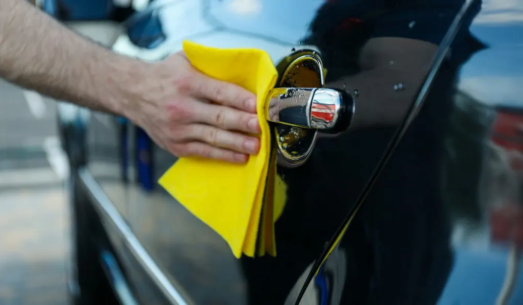 Man wiping rubs a car after washing , car wash concept