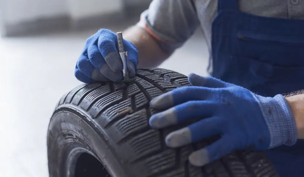Mechanic checking tire tread depth and wear