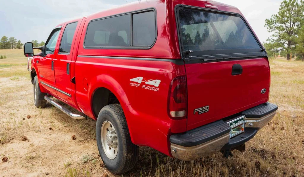Red pickup truck with toppers parked in an open field