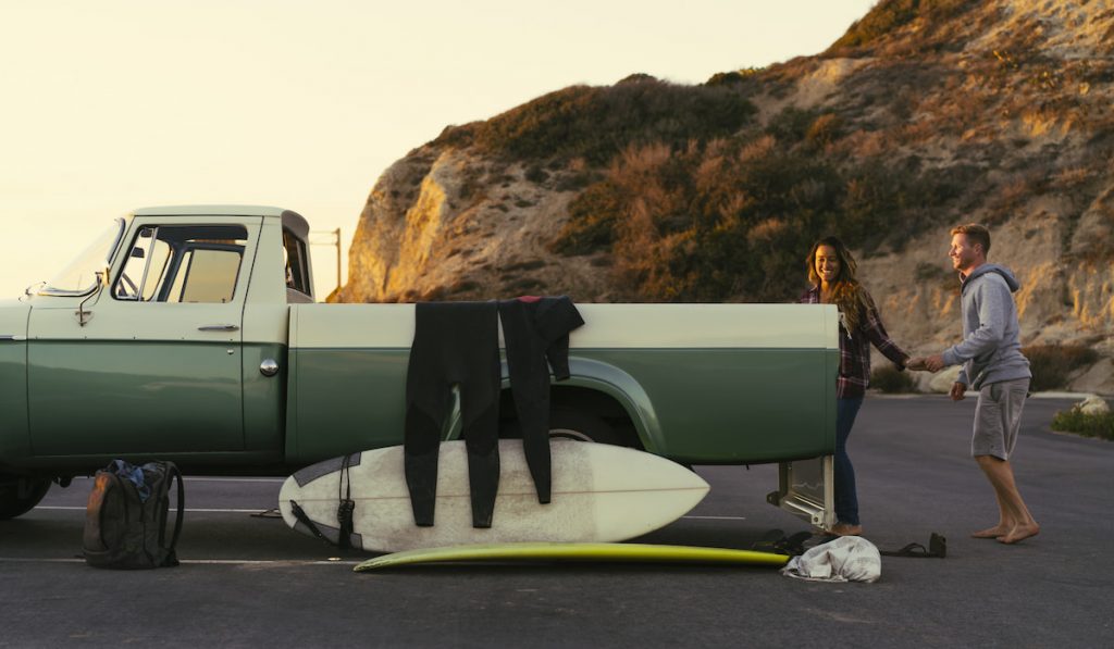 Surfing couple with pickup truck at Newport Beach, California, USA
