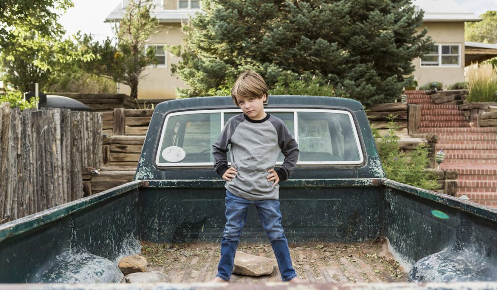 boy standing on dirty pickup truck bed