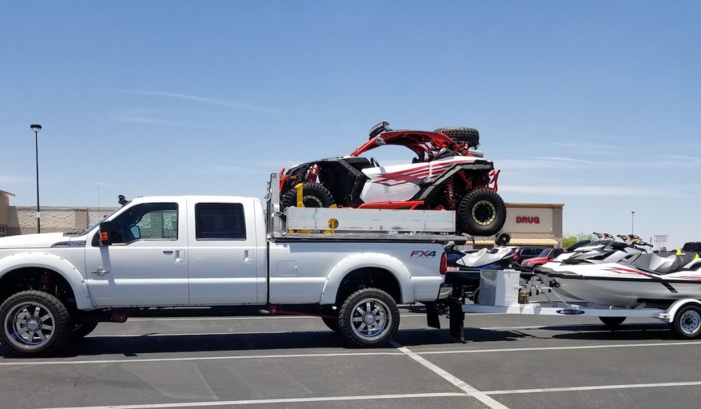 pickup truck with atv on bed and hauling jet ski